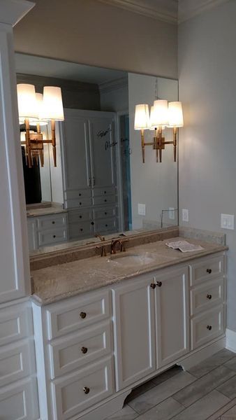 Bathroom vanity with double sink, large mirror, and wall sconces in a light-colored room