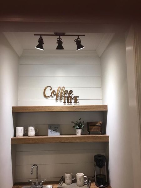 Built-in coffee nook with shelves, mugs, a coffee maker, and “Coffee” wall sign under track lights