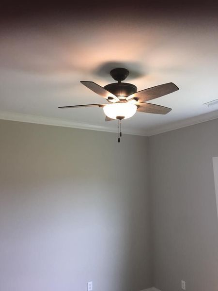 Empty beige room with a ceiling fan and light on a white ceiling, viewed upward from a corner