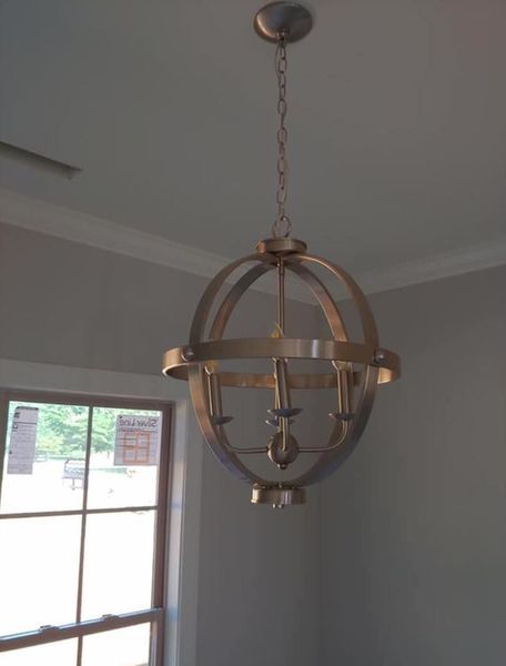 Bronze spherical pendant light hanging from the ceiling near a window in a gray room
