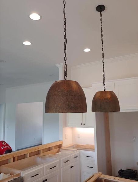 Two woven pendant lights hanging over a bright kitchen with white cabinets