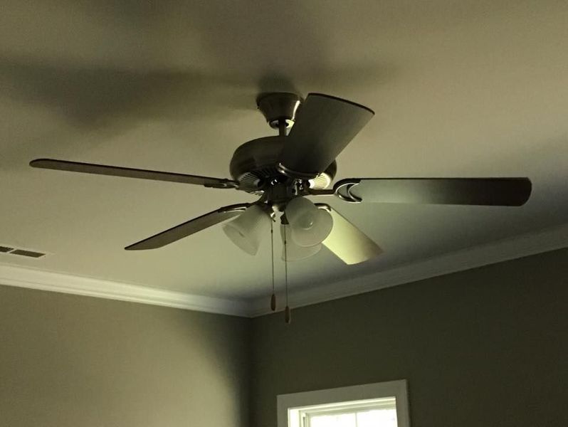 Ceiling fan with lights on a gray ceiling above a room corner and window