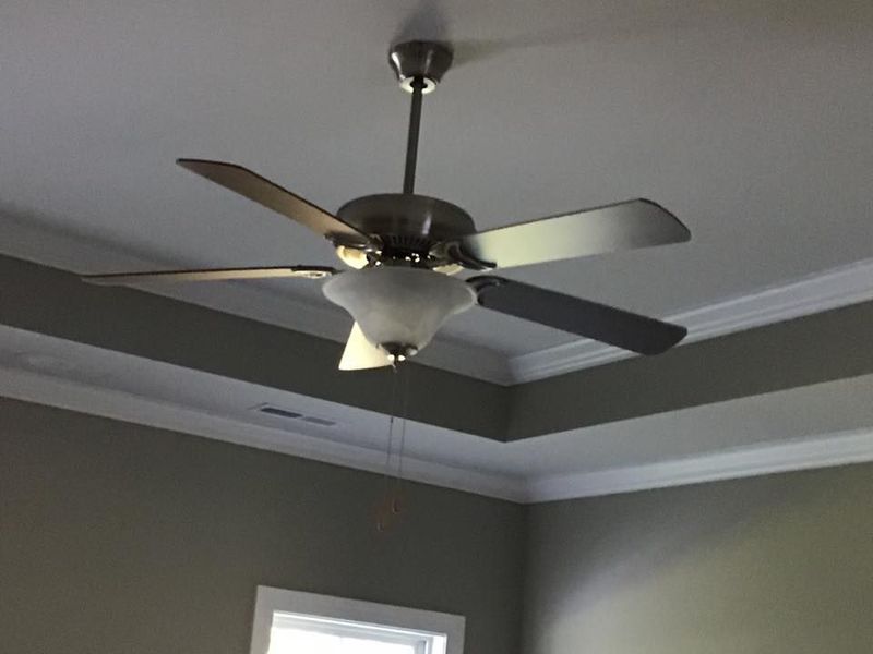 Modern ceiling fan with light in a gray room with crown molding
