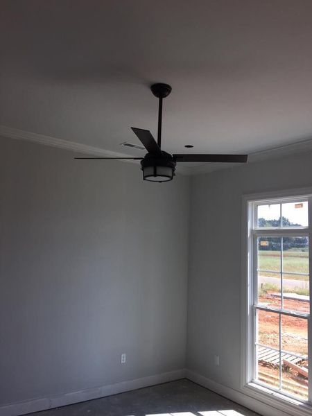Empty gray room with a ceiling fan and a window showing an outside view.