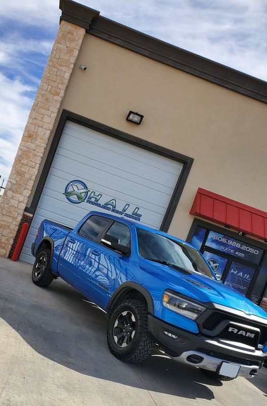 A blue ram truck is parked in front of a building.