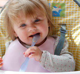 a small girl biting spoon