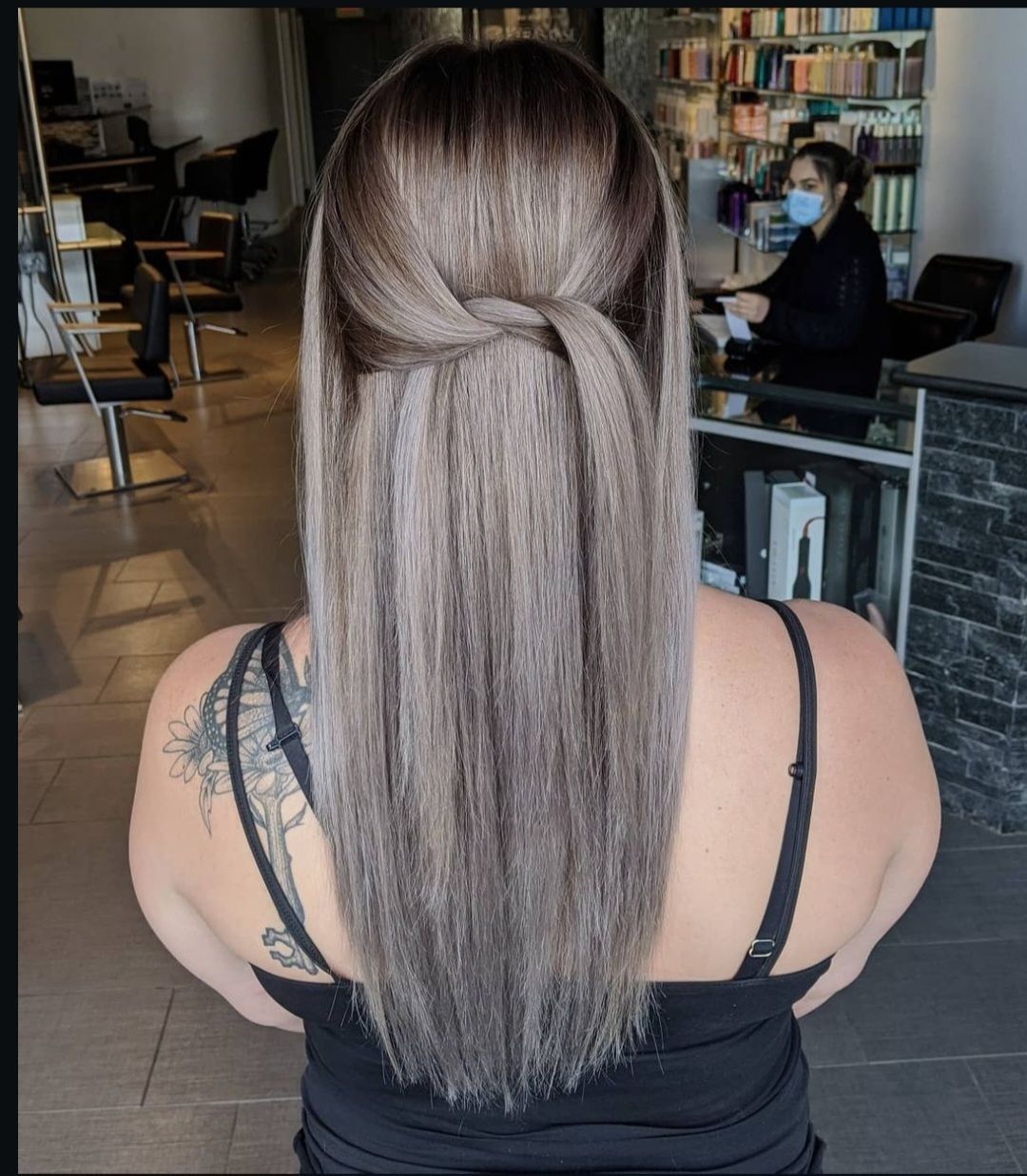 A woman with long hair is wearing a black tank top