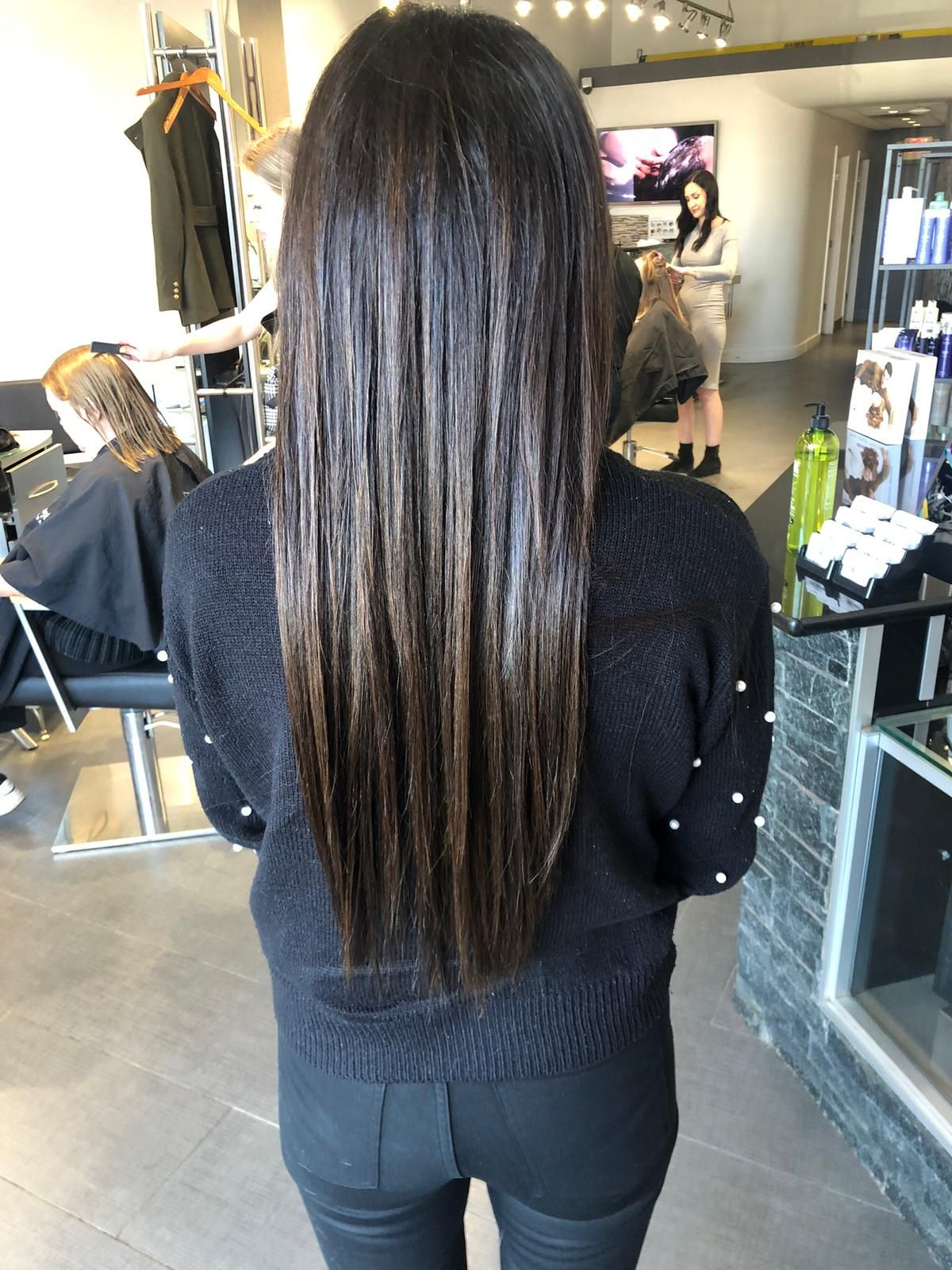 A woman with long hair is standing in a salon.