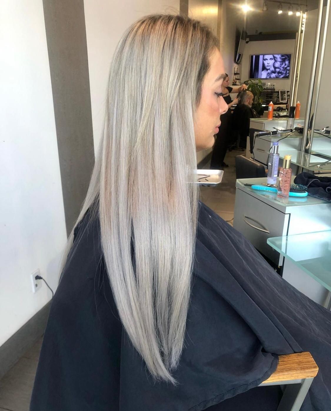 A woman with long blonde hair is getting her hair cut in a salon.