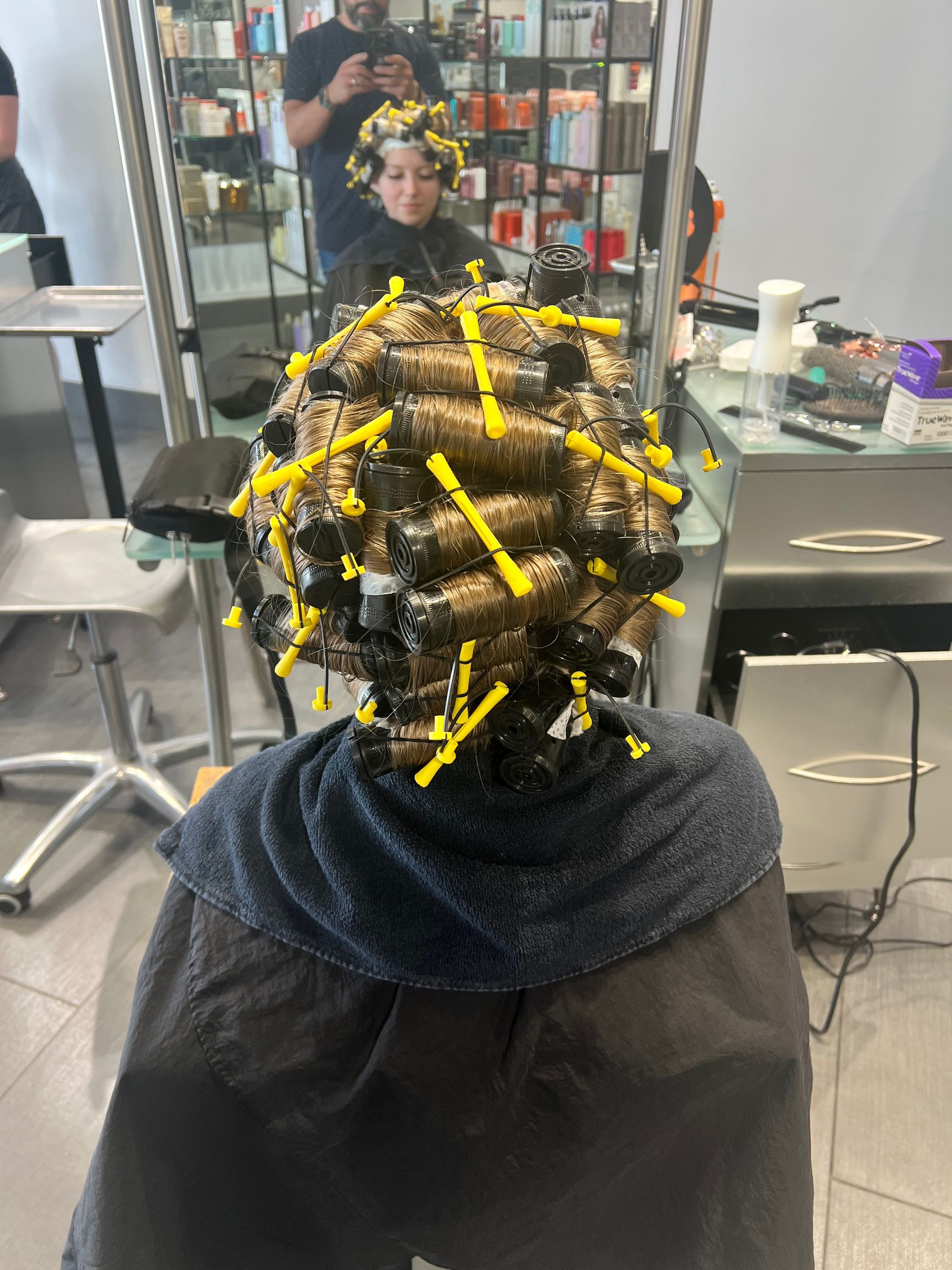A woman is getting her hair curled in a salon.