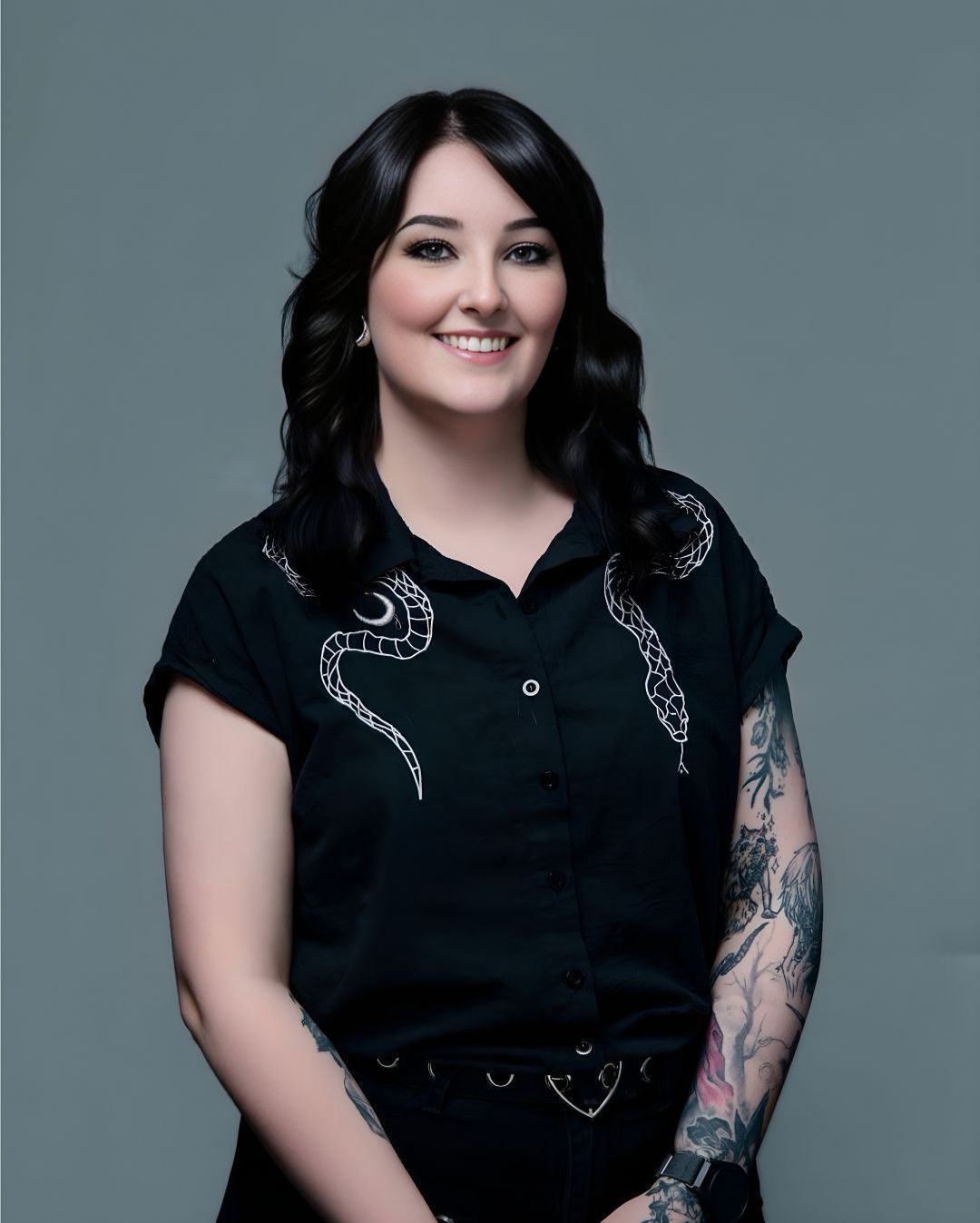 A woman with a tattoo on her arm is wearing a black shirt.