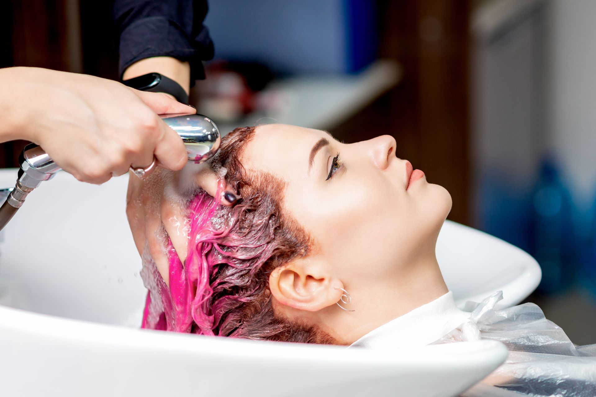 A woman is getting her hair washed in a sink at a salon.