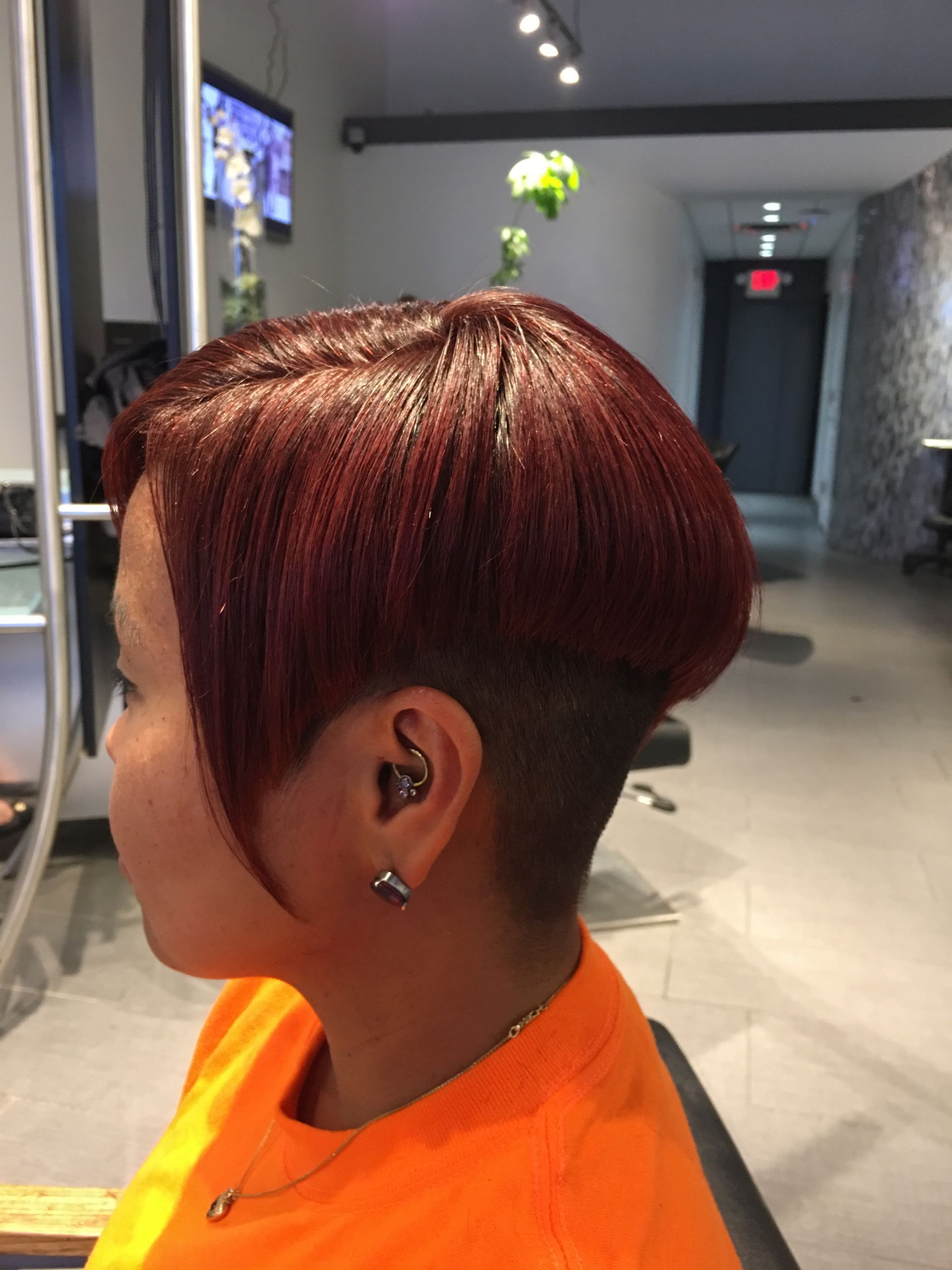 A woman with red hair is getting her hair cut in a salon.