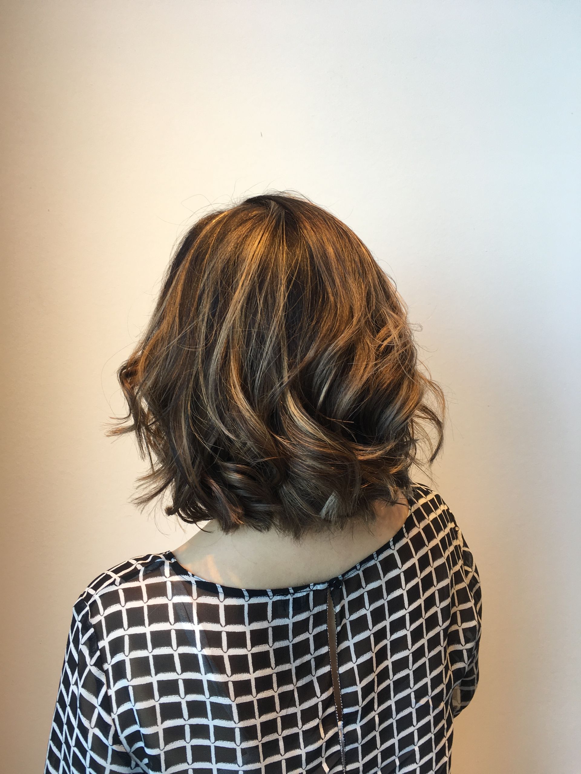 A woman with short brown hair is wearing a black and white checkered shirt.