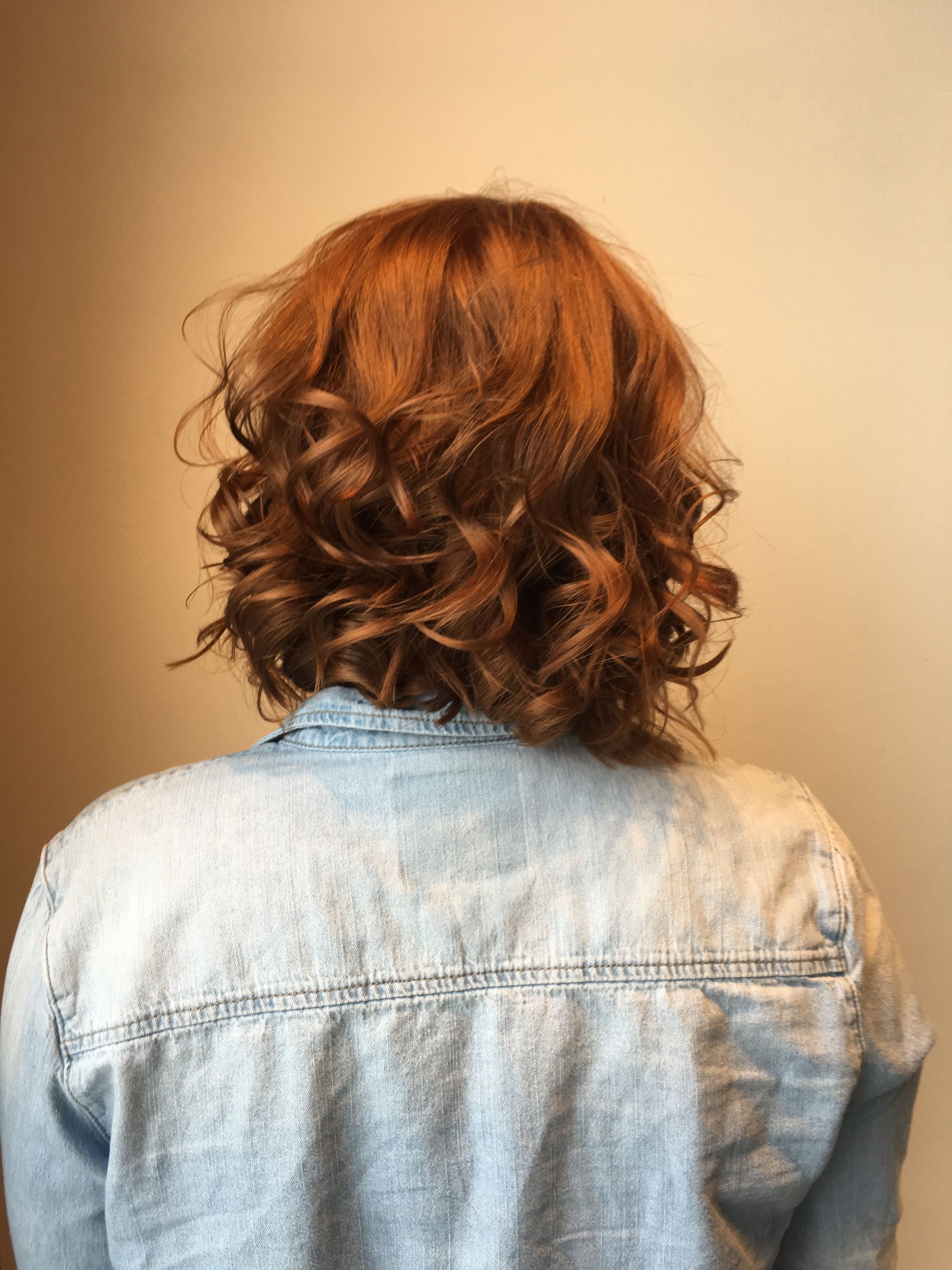 A woman with red curly hair is wearing a denim jacket.