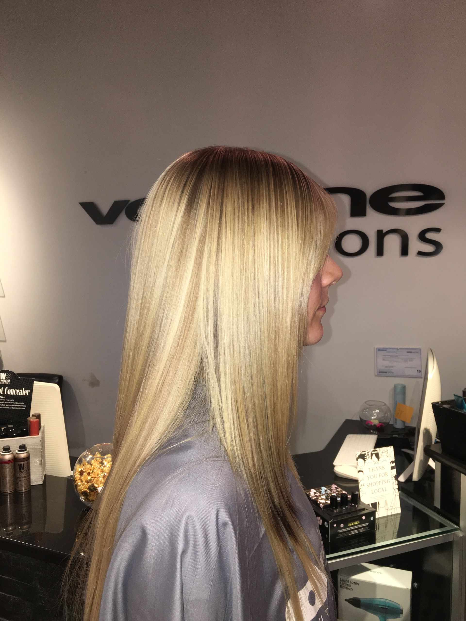 A woman with long blonde hair is standing in front of a wall with the word ons on it