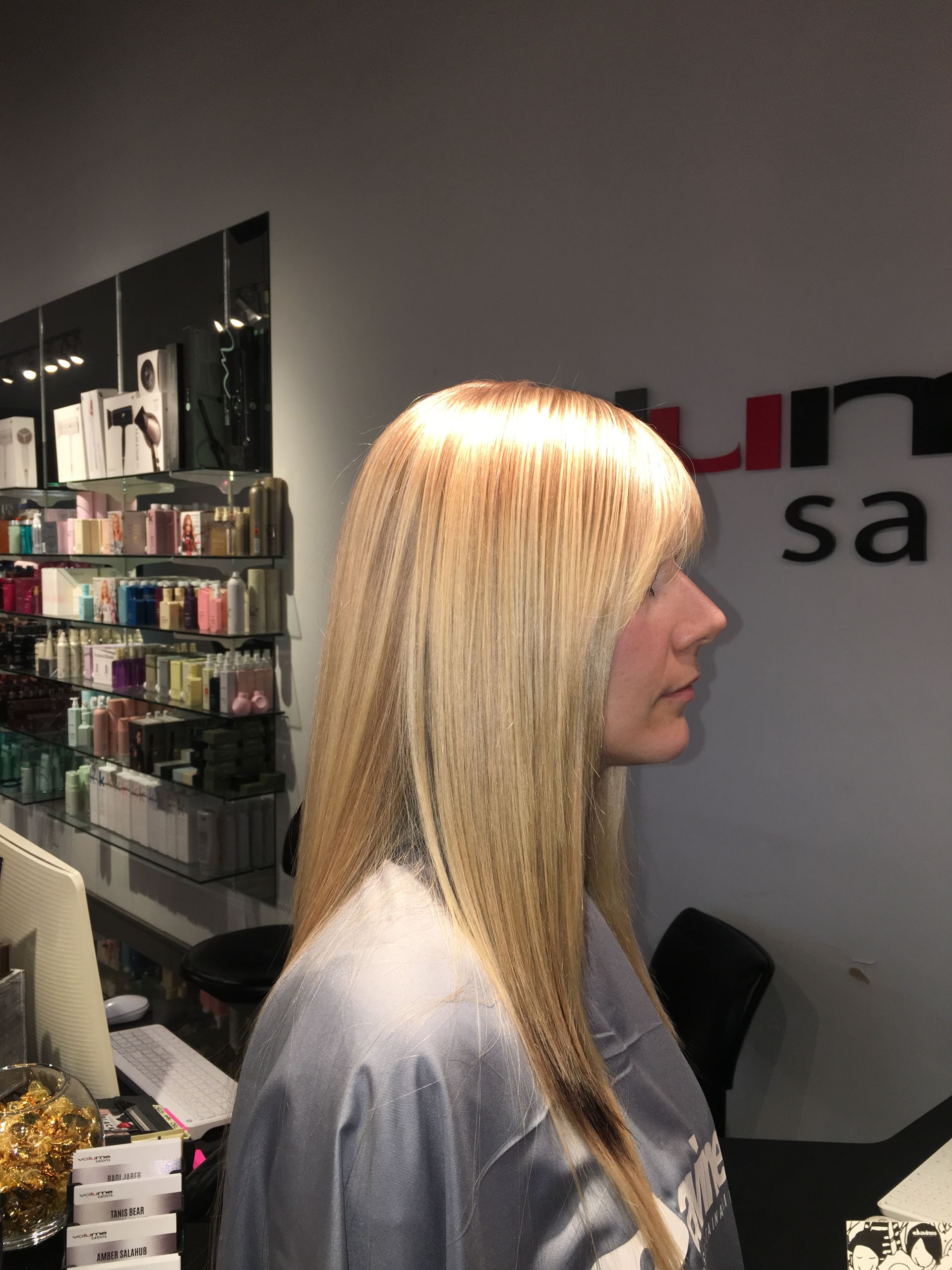 A woman with long blonde hair is standing in front of a sign that says un sa