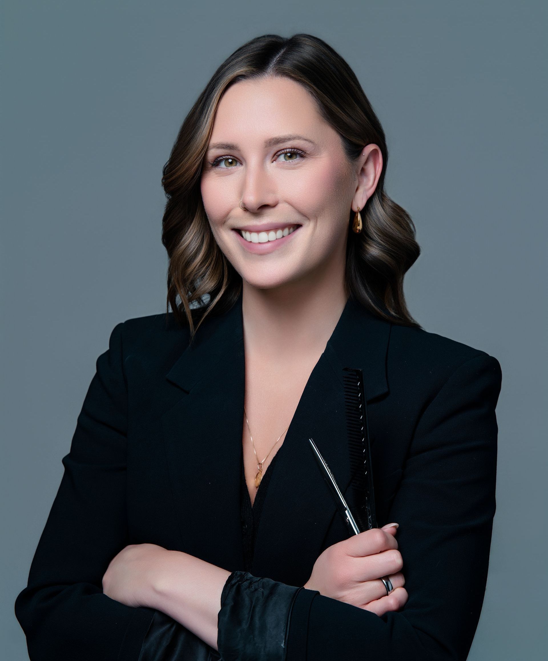 A woman in a black jacket is smiling with her arms crossed.