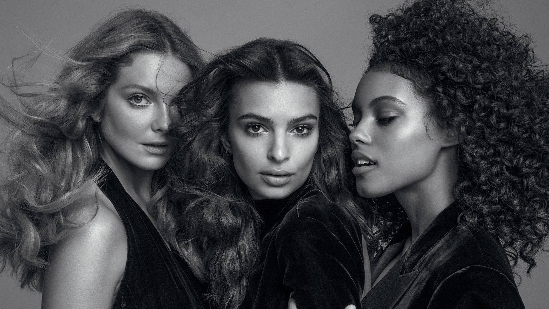 a black and white photo of three women standing next to each other .