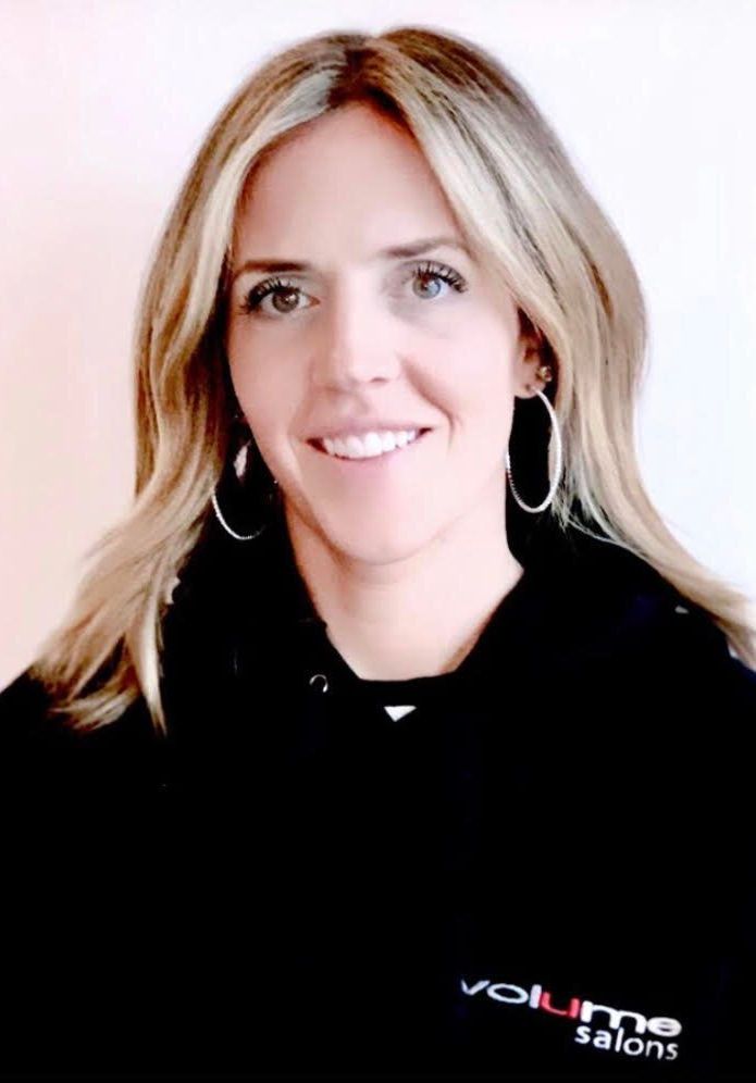 A woman wearing a black shirt that says volume salons