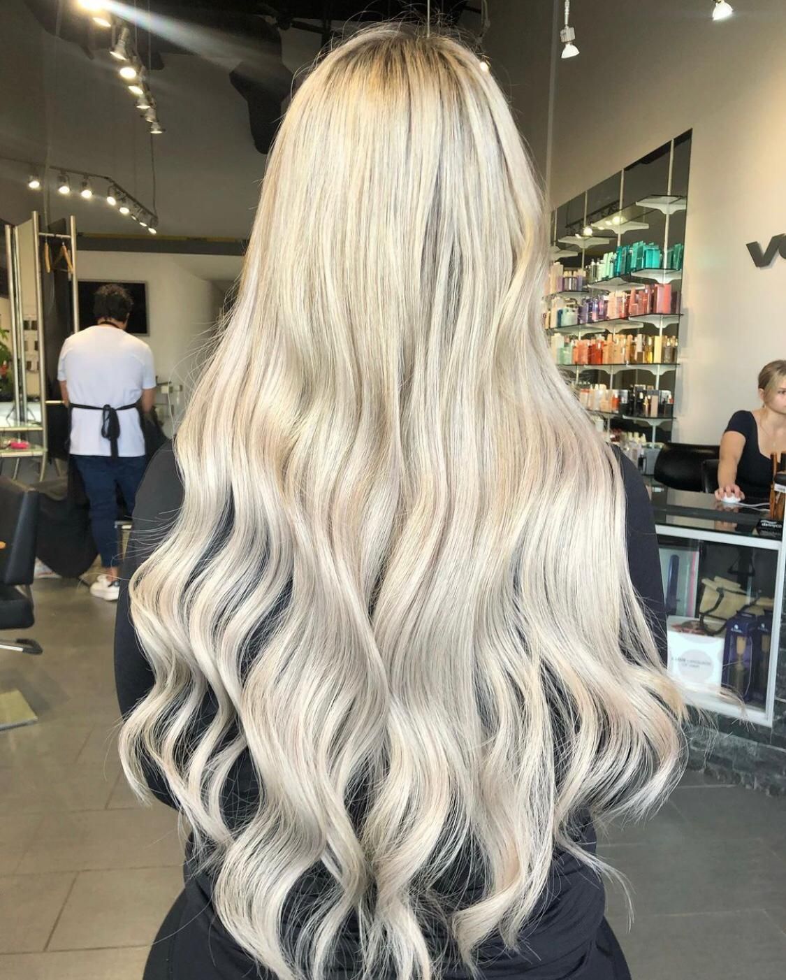 A woman with long blonde hair is standing in a salon.