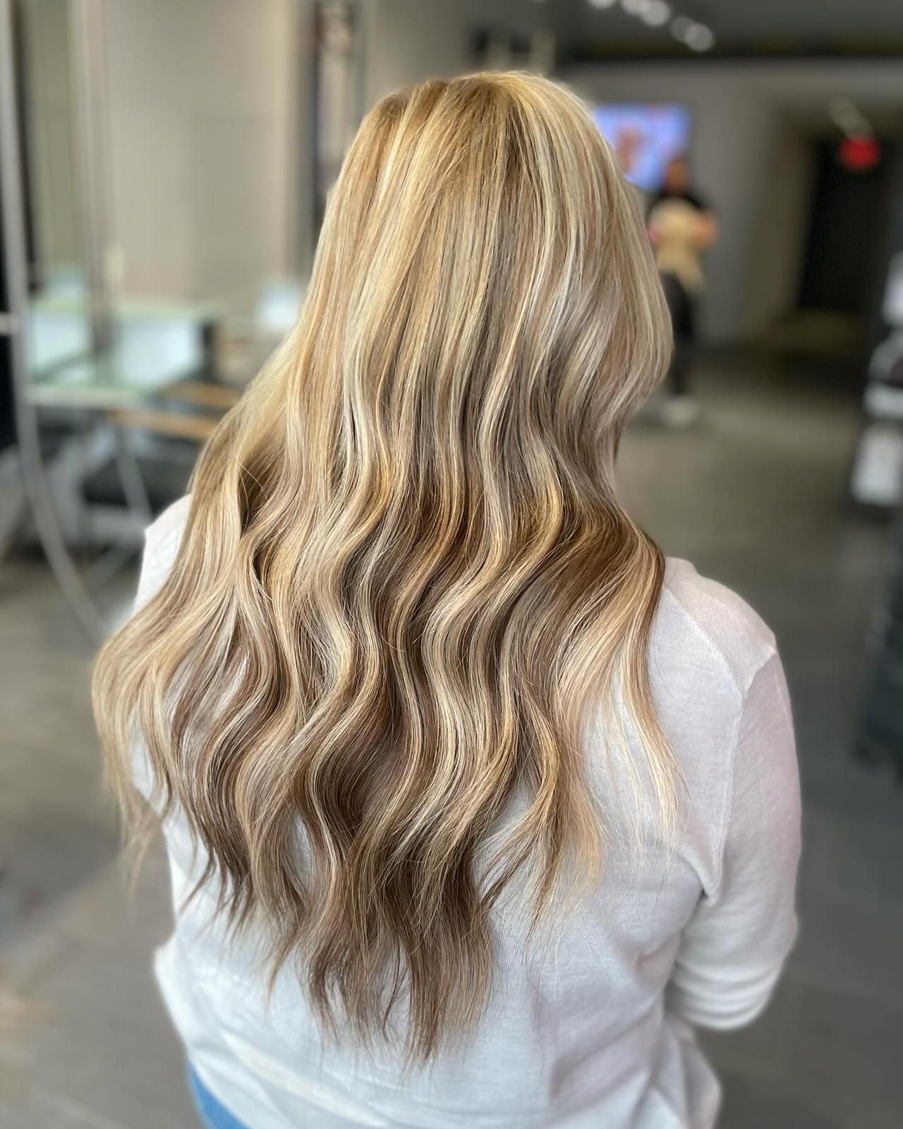A woman with long blonde hair is standing in a salon.