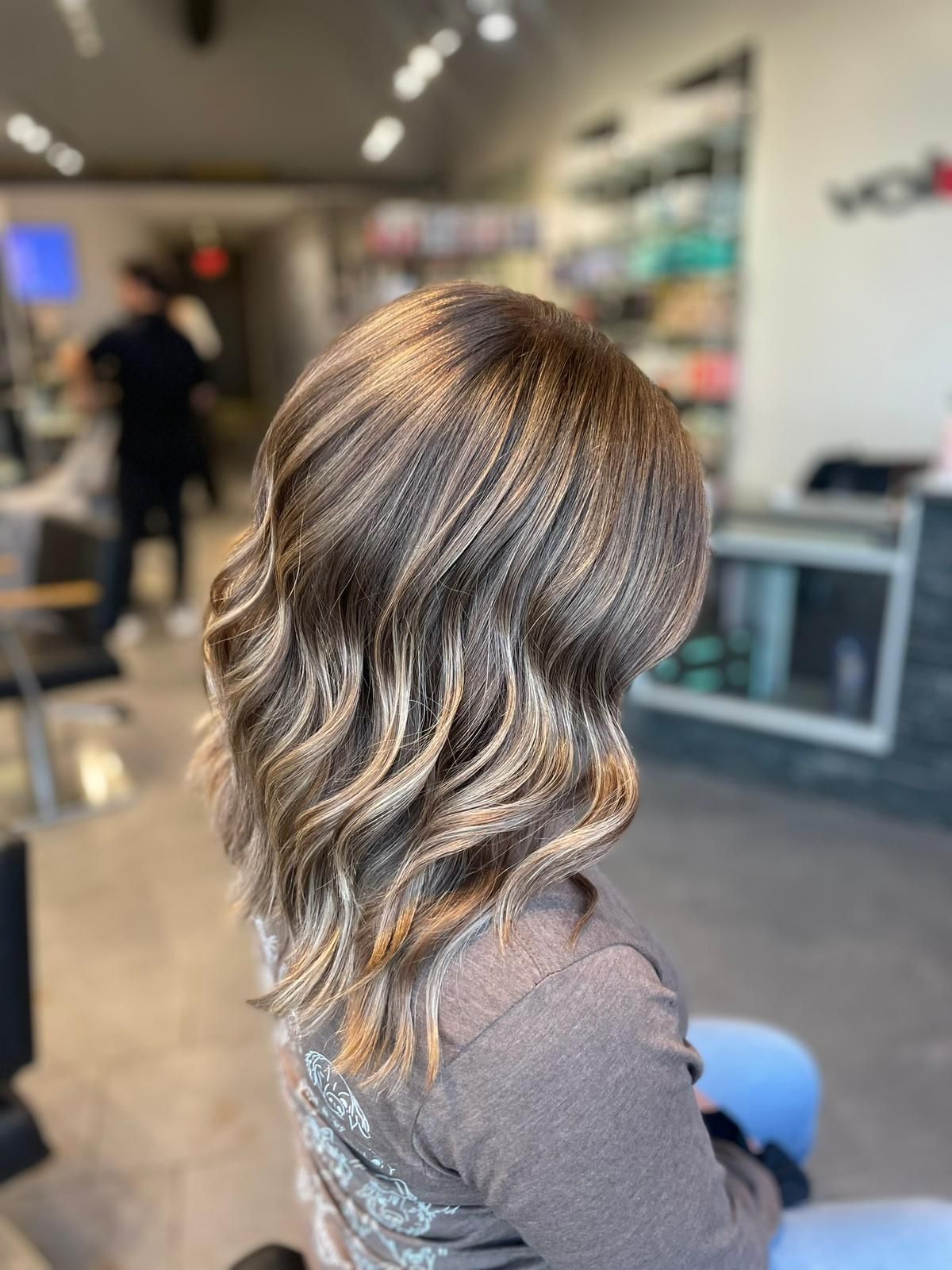 A woman is sitting in a chair with her hair in a salon.