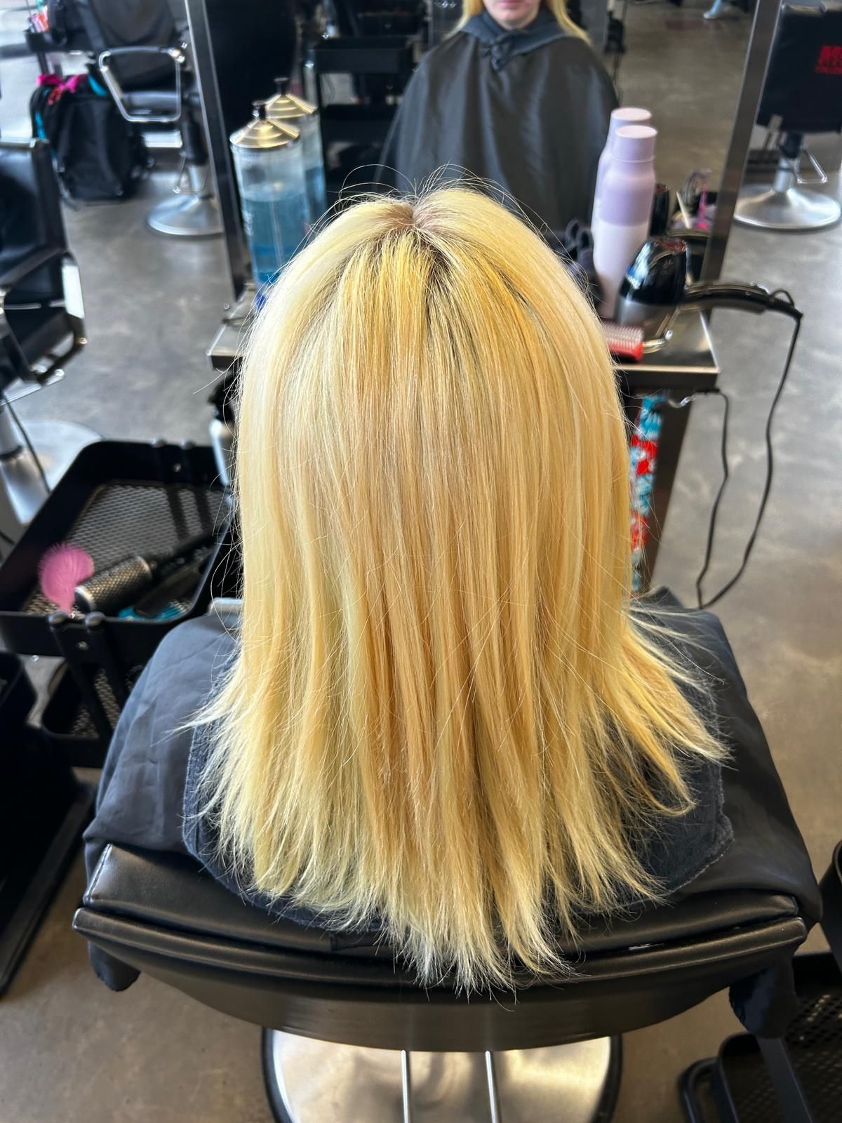 A woman with blonde hair is sitting in a chair in a salon.