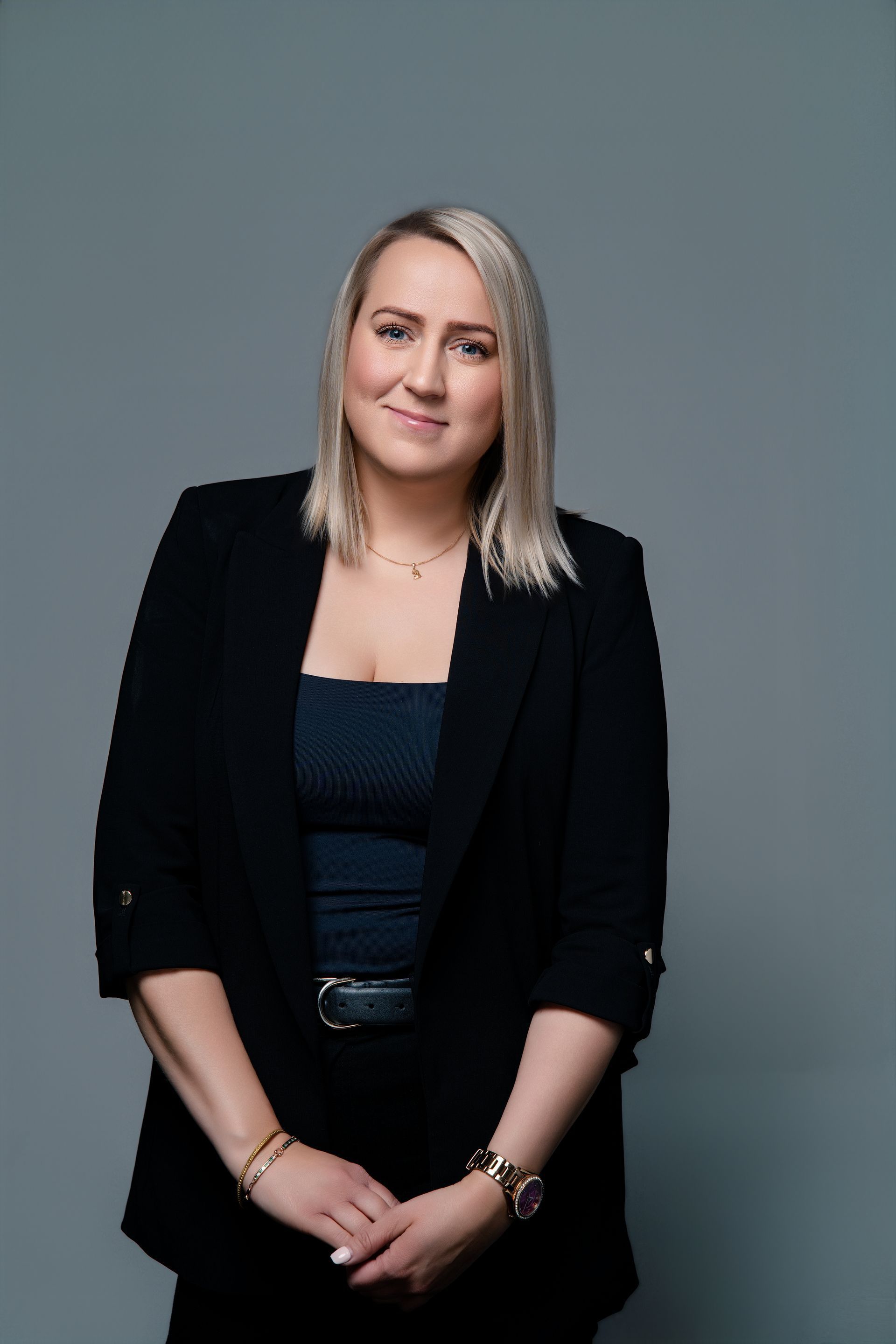 A woman in a black off the shoulder top smiles for the camera