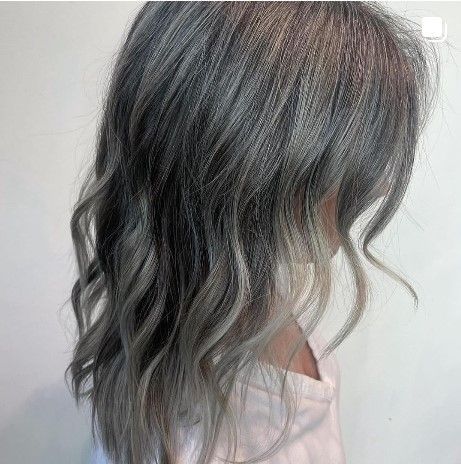 a woman with gray hair is wearing a pink shirt .