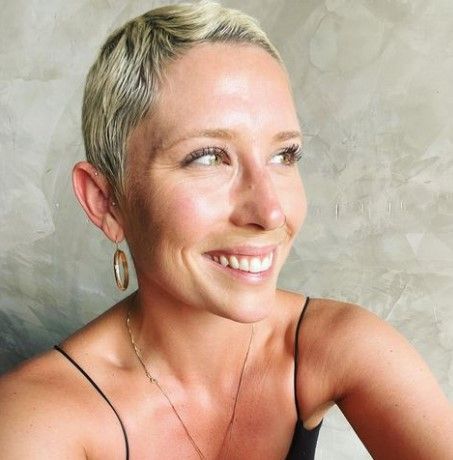 a woman with short blonde hair and hoop earrings is smiling .