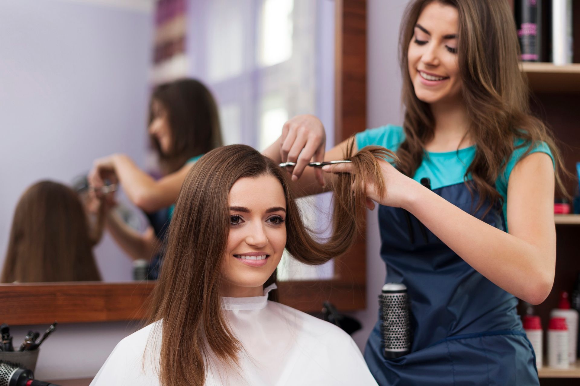 A woman is getting her hair cut by a hairdresser in a salon.