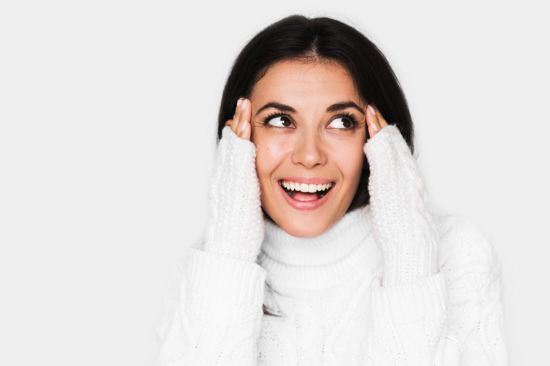 A woman in a white sweater is smiling and looking up.