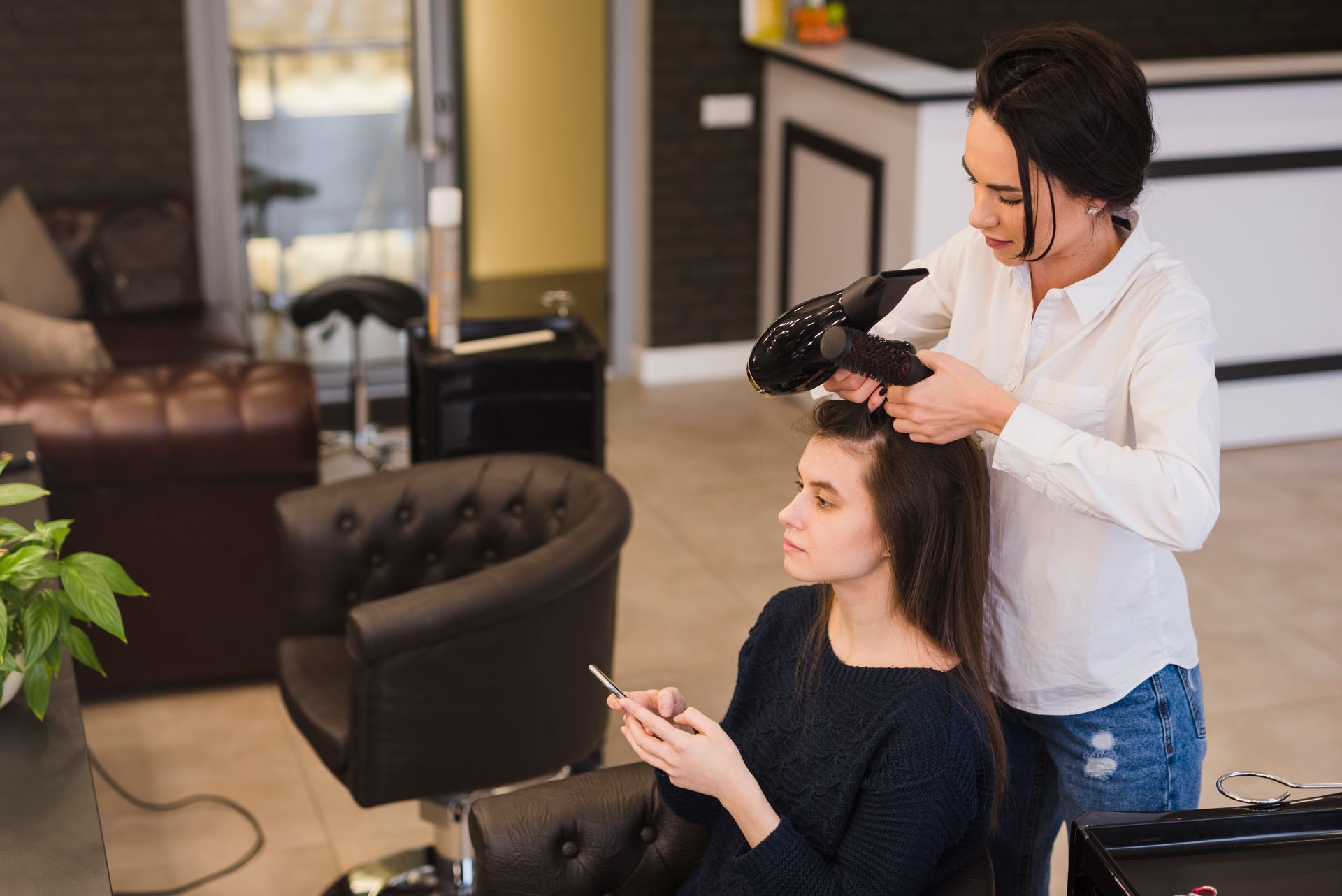 A woman is getting her hair blow dried by a hairdresser in a salon.