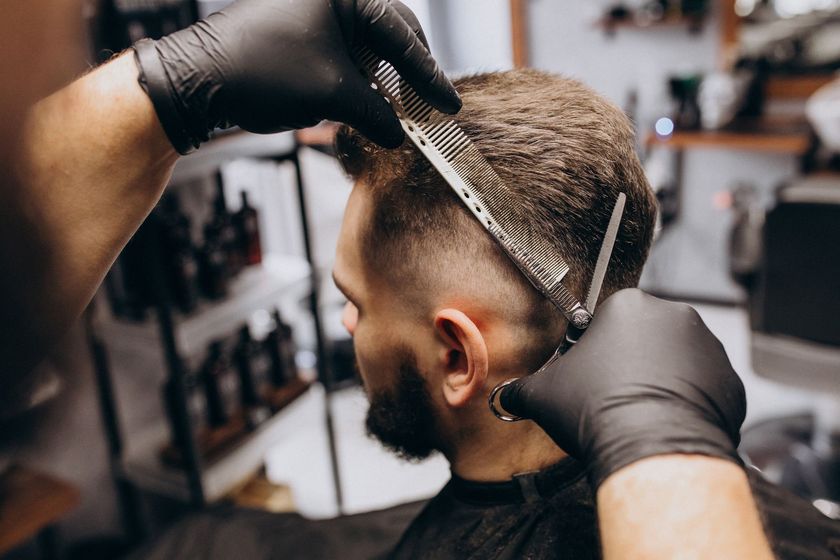 a man is getting his hair cut by a barber in a barber shop .