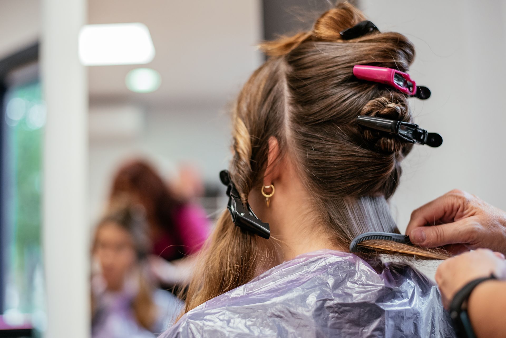 A woman is getting her hair done by a hairdresser in a salon.