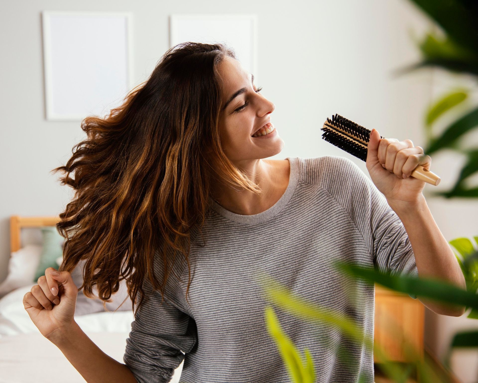 A woman is brushing her hair with a brush while singing into it.