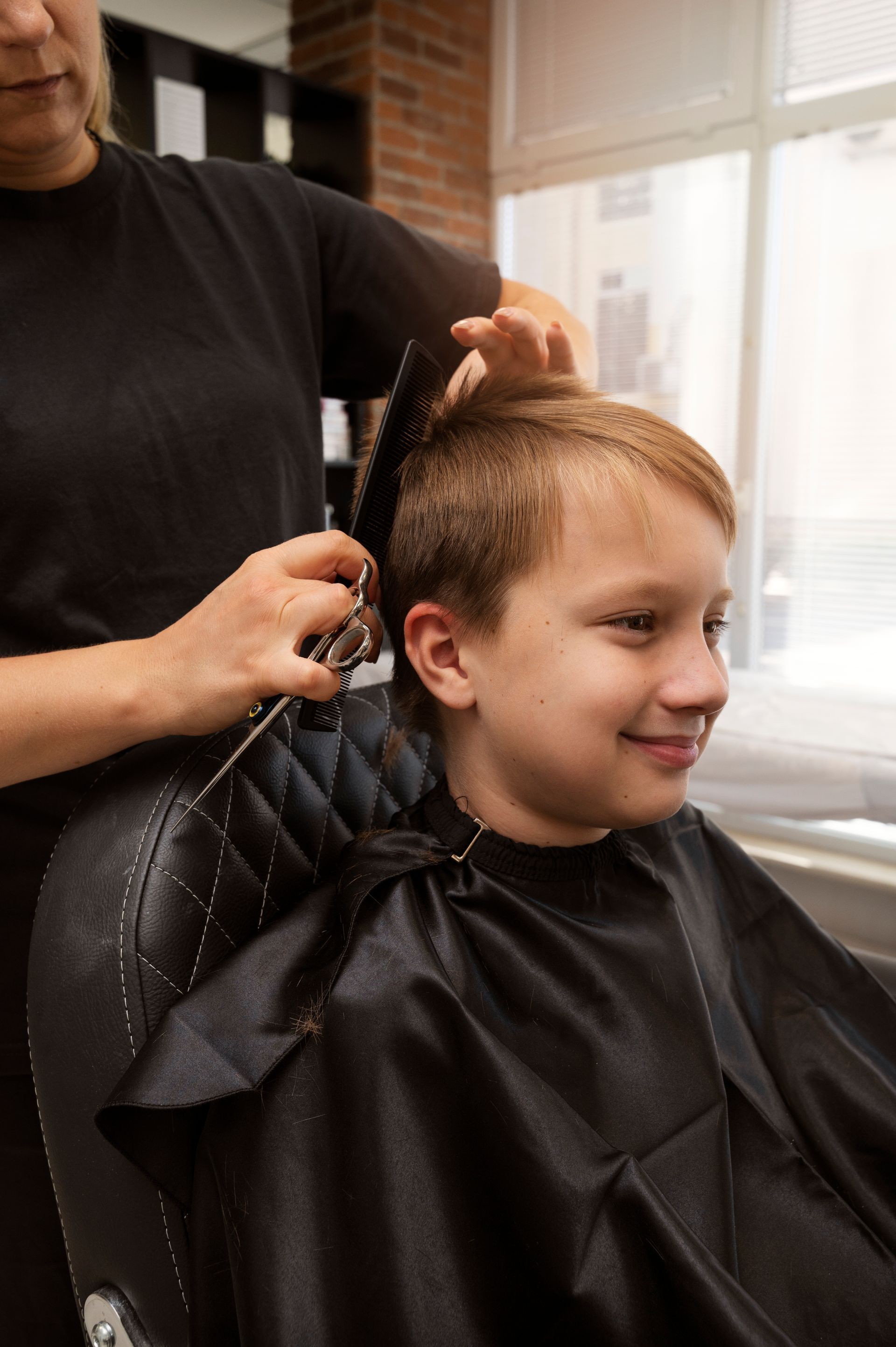 a young boy is getting his hair cut at a barber shop .