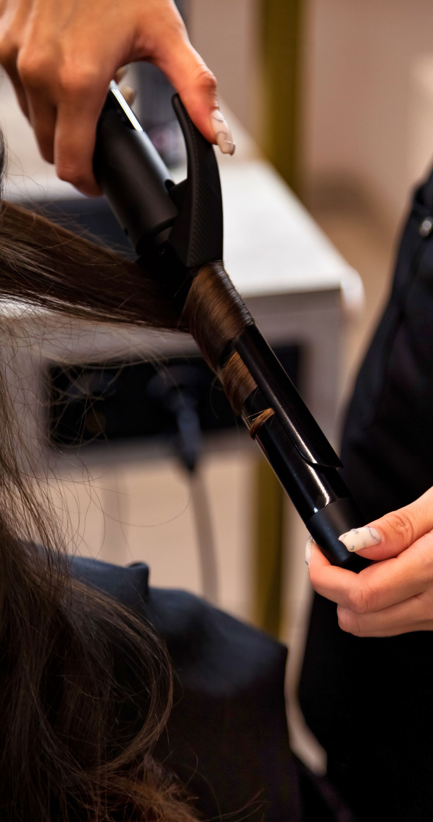 A woman is getting her hair straightened by a hairdresser.