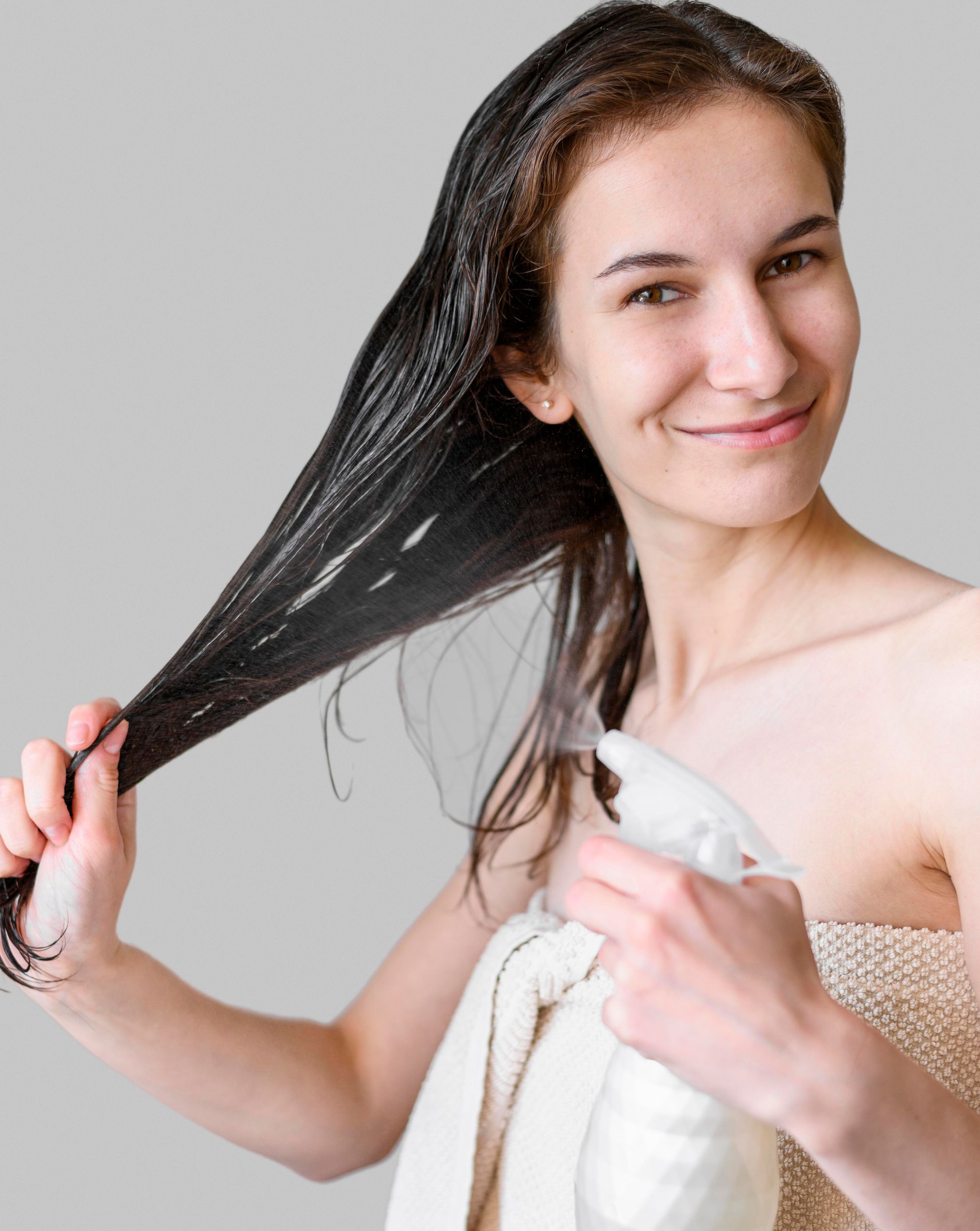 a woman is spraying her hair with a spray bottle