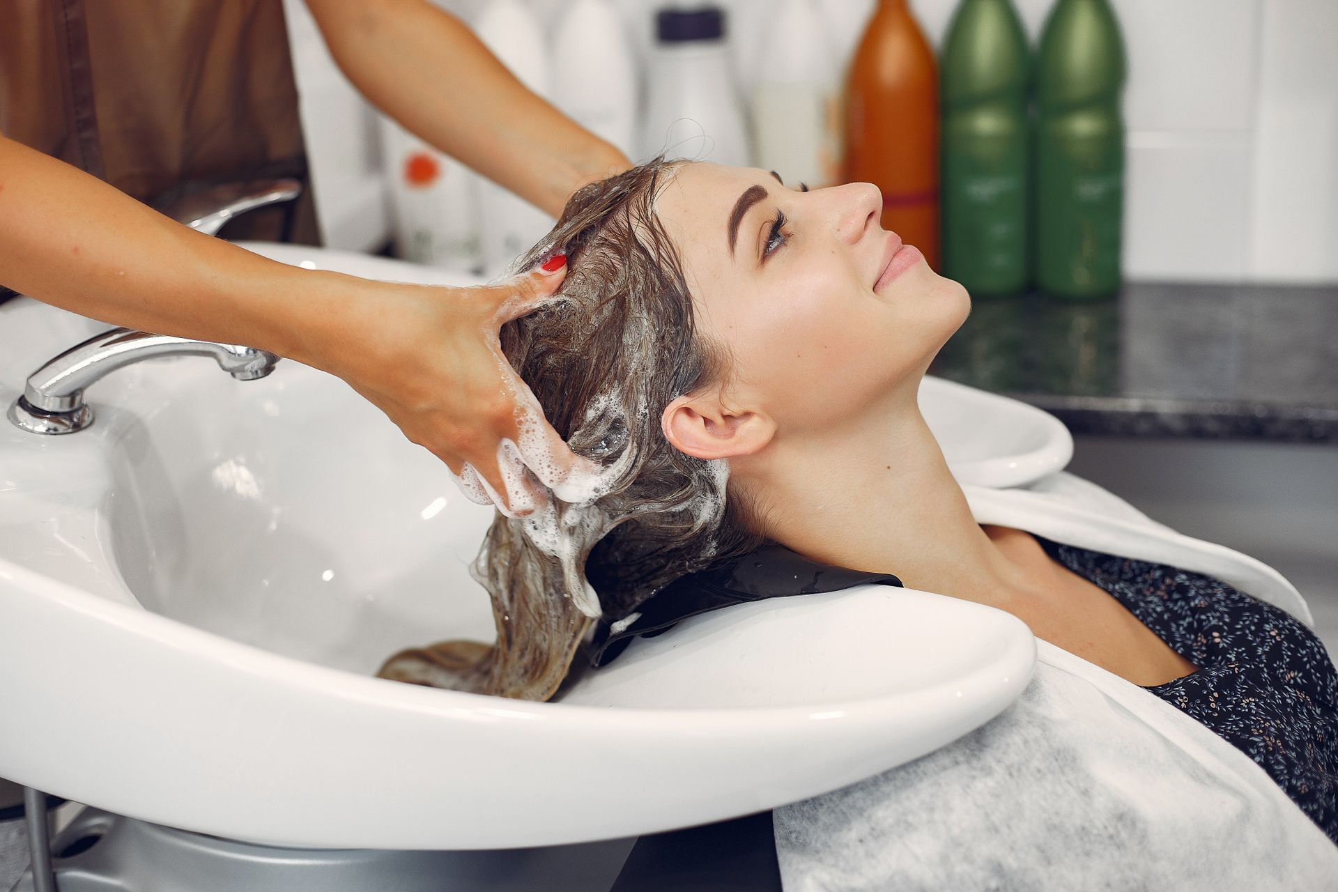 A woman is washing her hair in a sink at a hair salon.