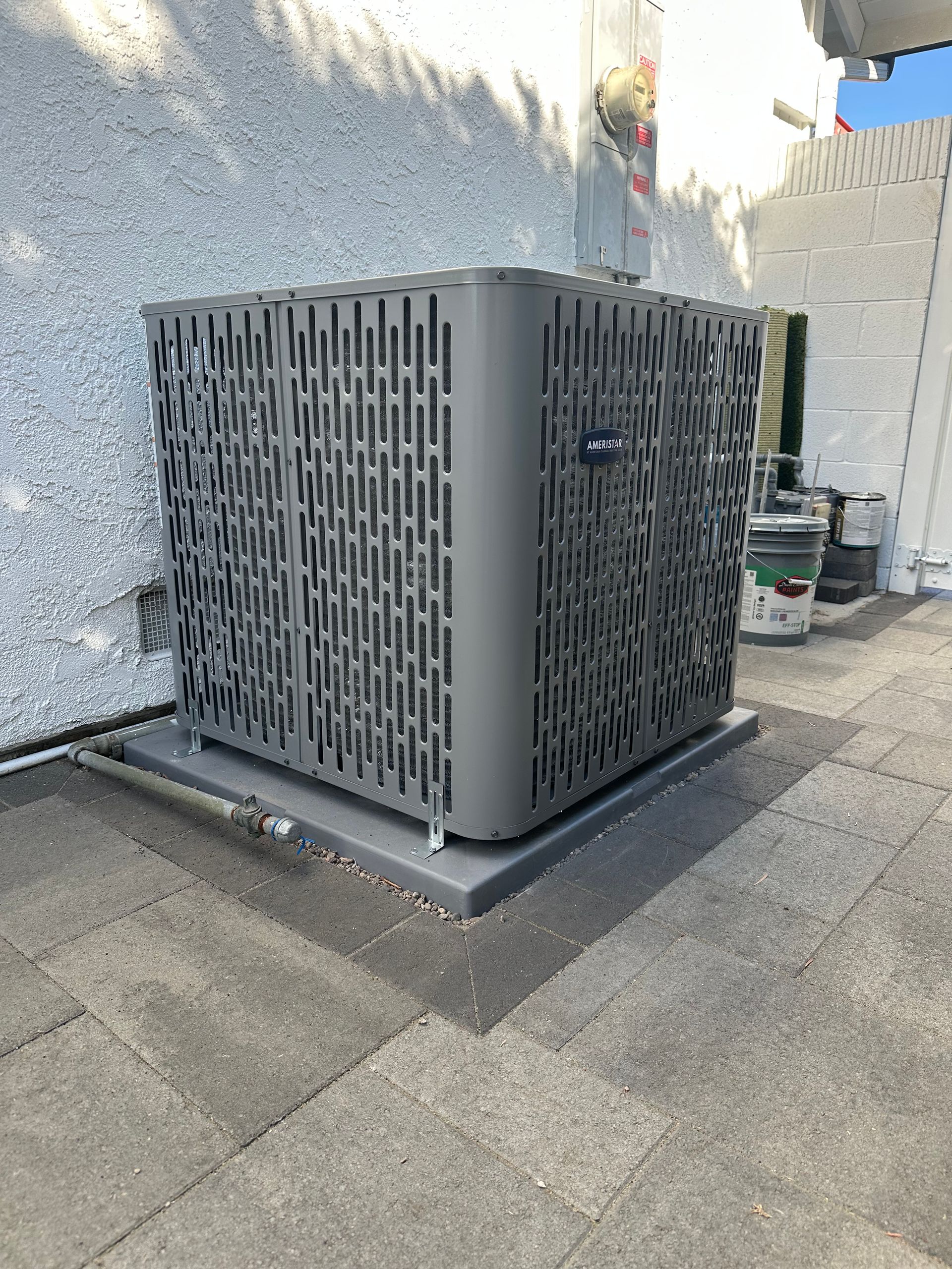 Gray air conditioning unit on a dark gray platform, mounted on a roof.