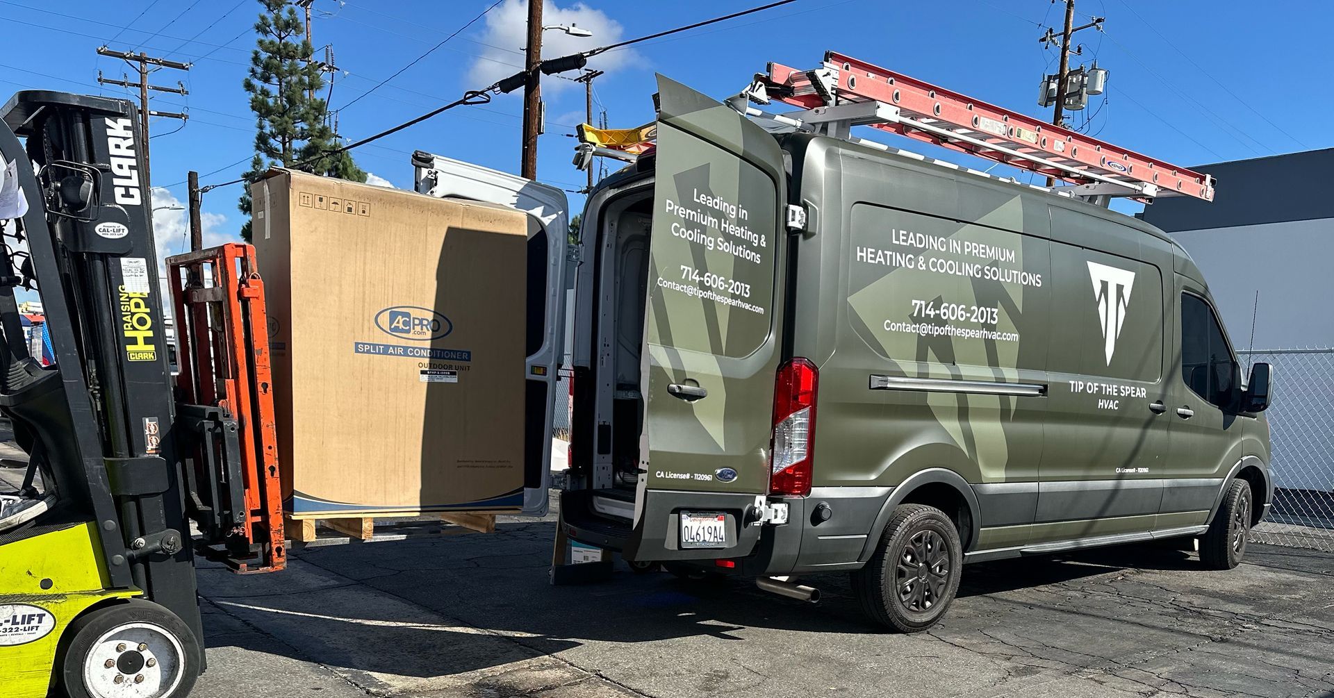 Forklift loading a large box onto a green service van with open doors.