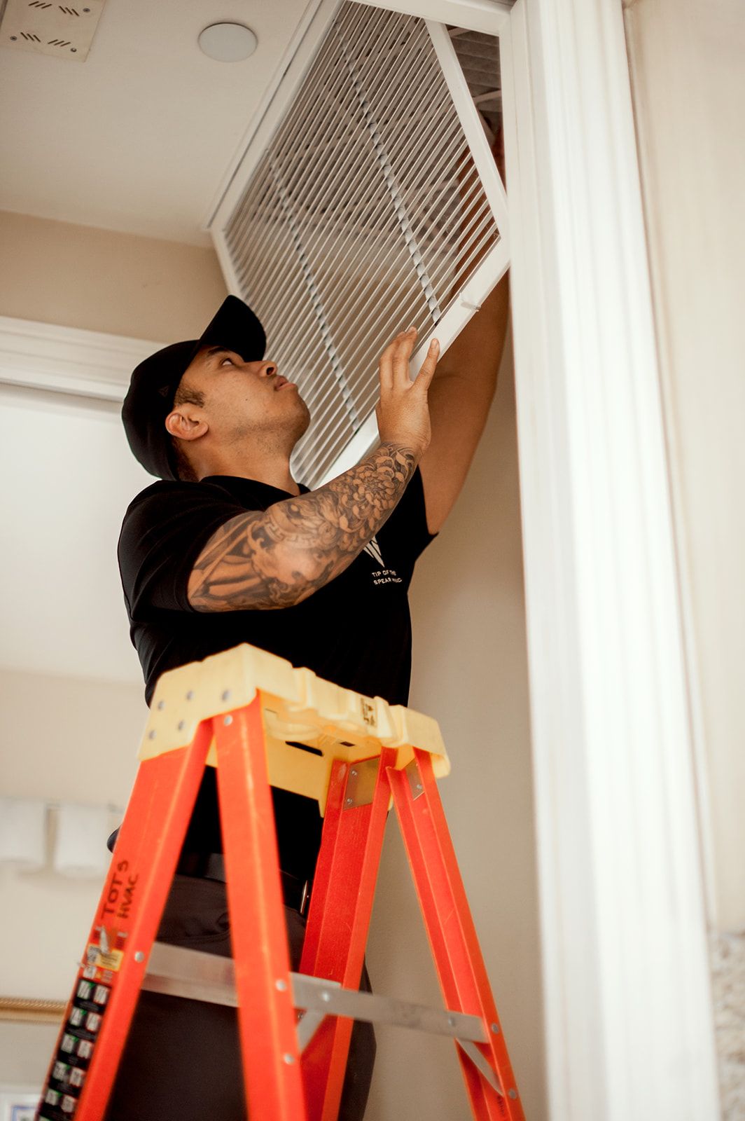 Person on a ladder installing an air filter in a ceiling.
