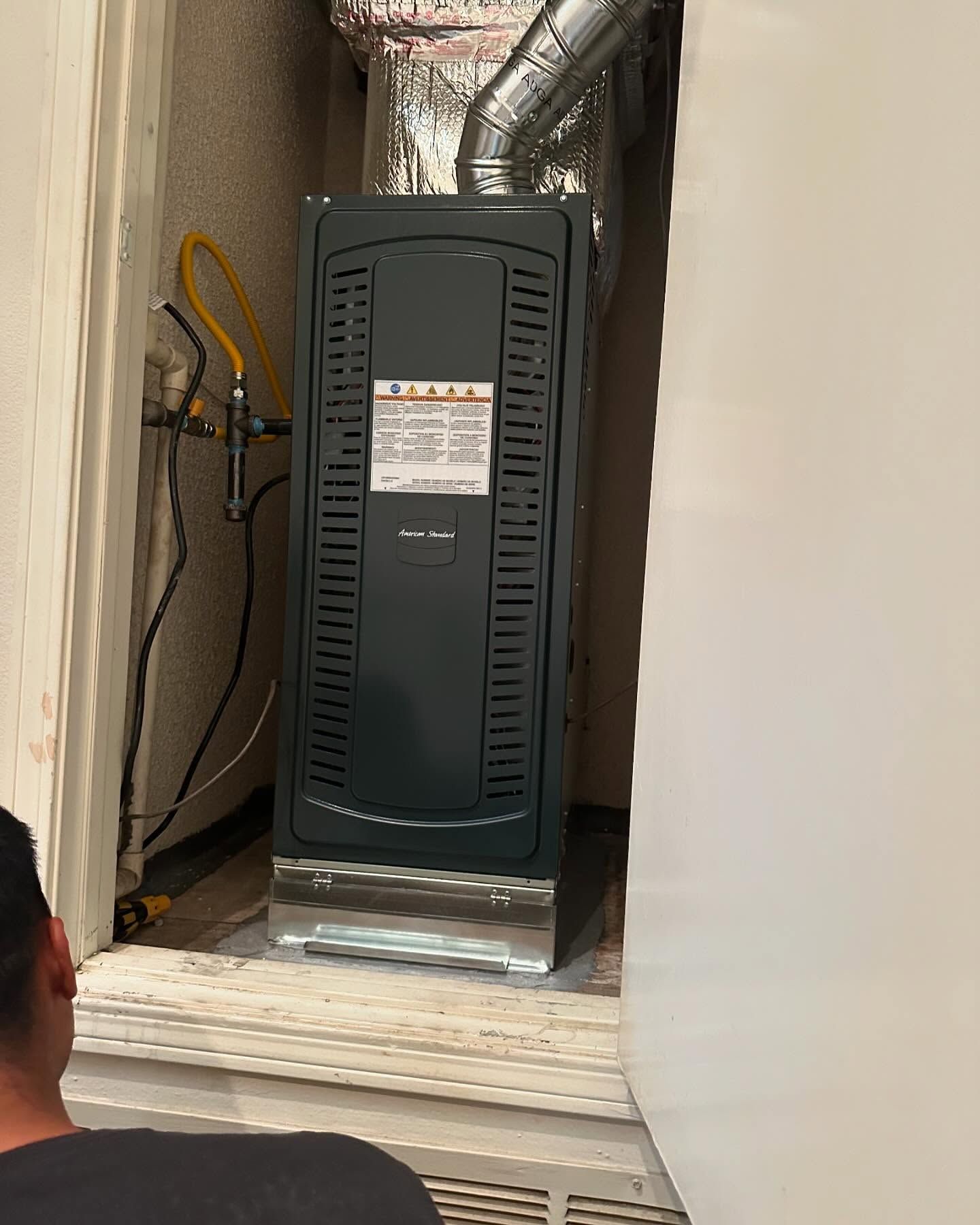 Tip of the Spear HVAC  | a man is looking at an air conditioner in a room.