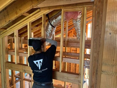 HVAC technician performing air duct installation in attic for new construction in Southern California