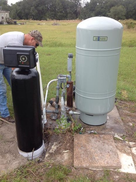 A man is working on a water treatment system in a field.
