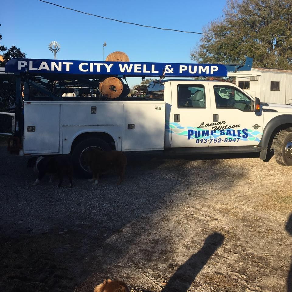 A plant city well and pump truck is parked in a gravel lot