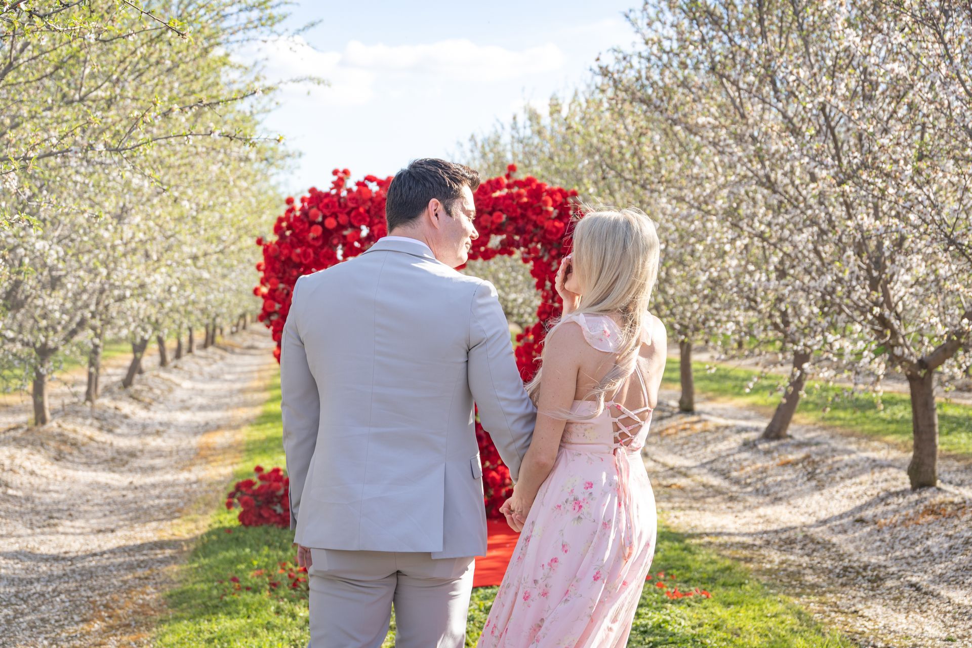 Couple embracing, about to kiss; woman smiles, man's hands on her face. Outdoors, black and white.