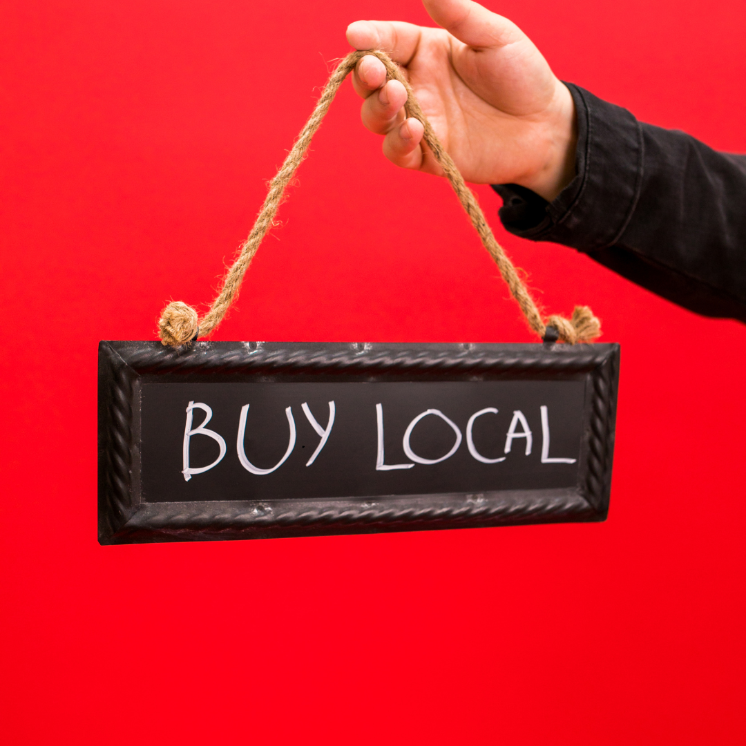 A person is holding a sign that says buy local